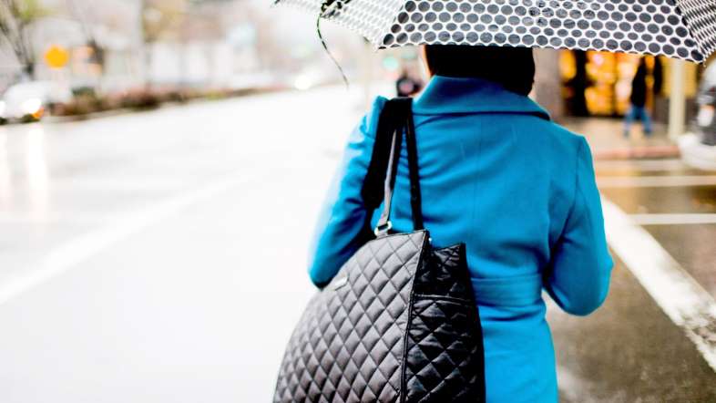 A lady is carrying a big black handbag.