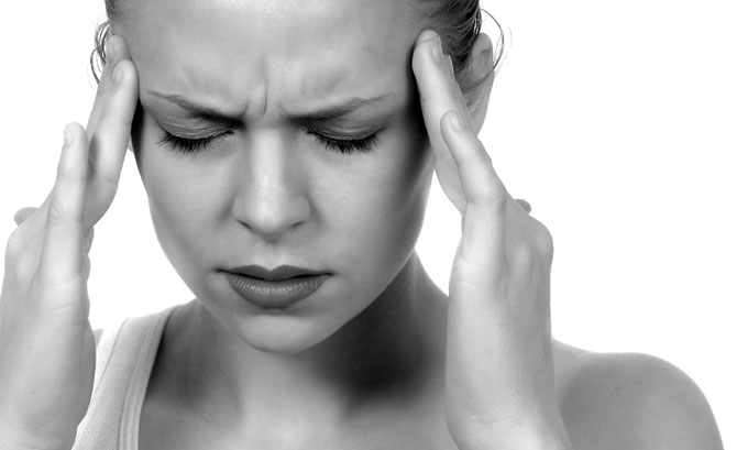 Female grimacing and massaging temple with fingers