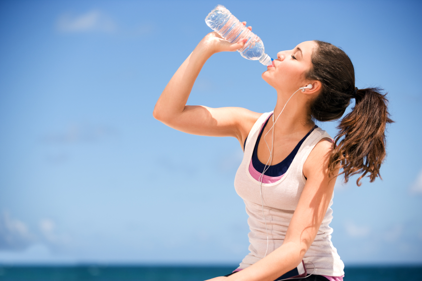 A young woman drinking water from a bottle while exercising